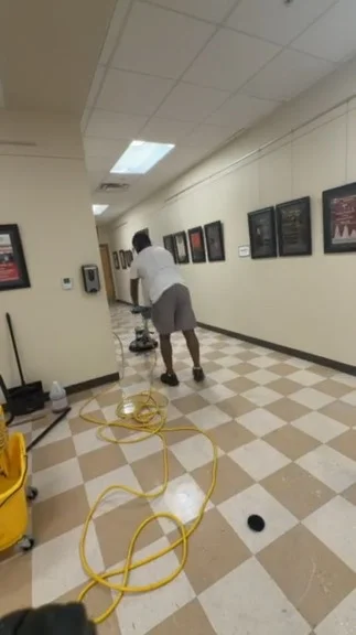 Aquamen worker operating a floor machine in a corridor