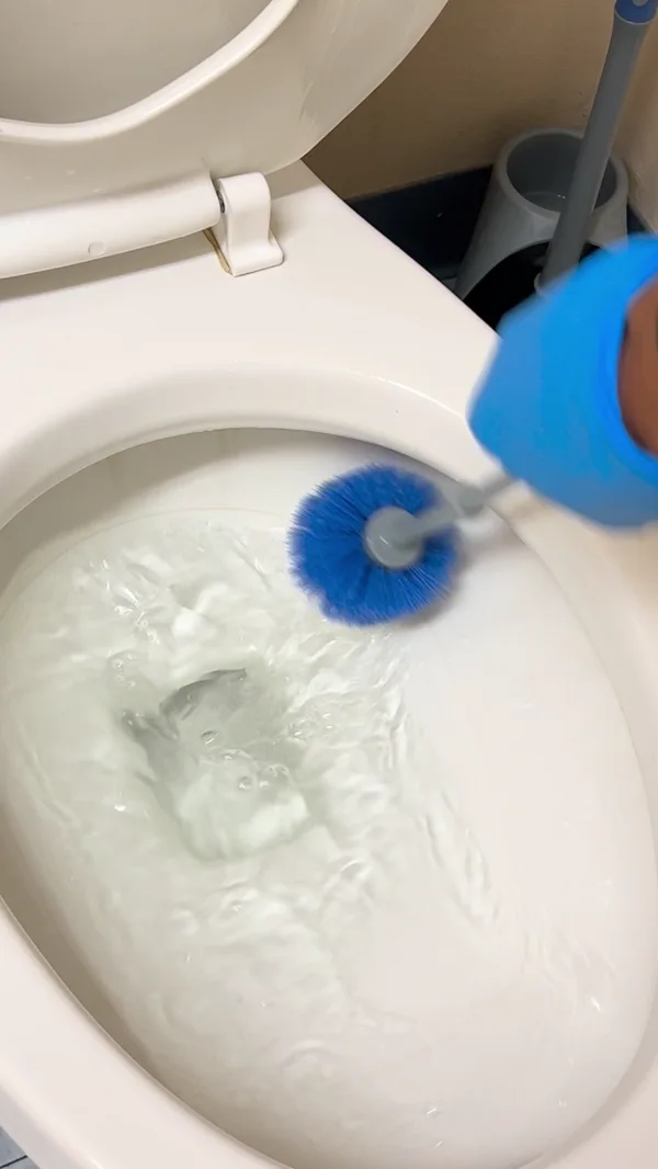 A gloved Aquamen worker brushing a toilet bowl during cleaning